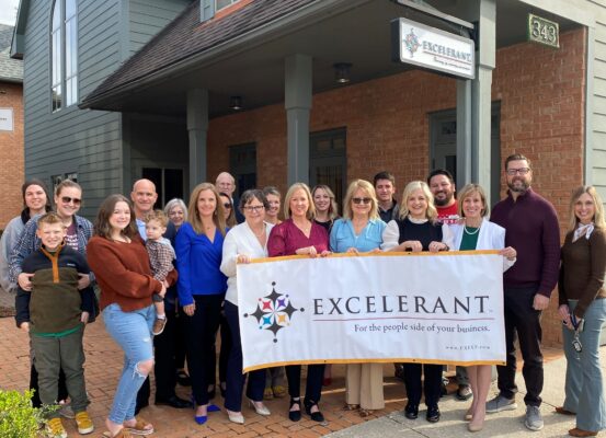 Excelerant partners and friends holding a banner to celebrates 20 years